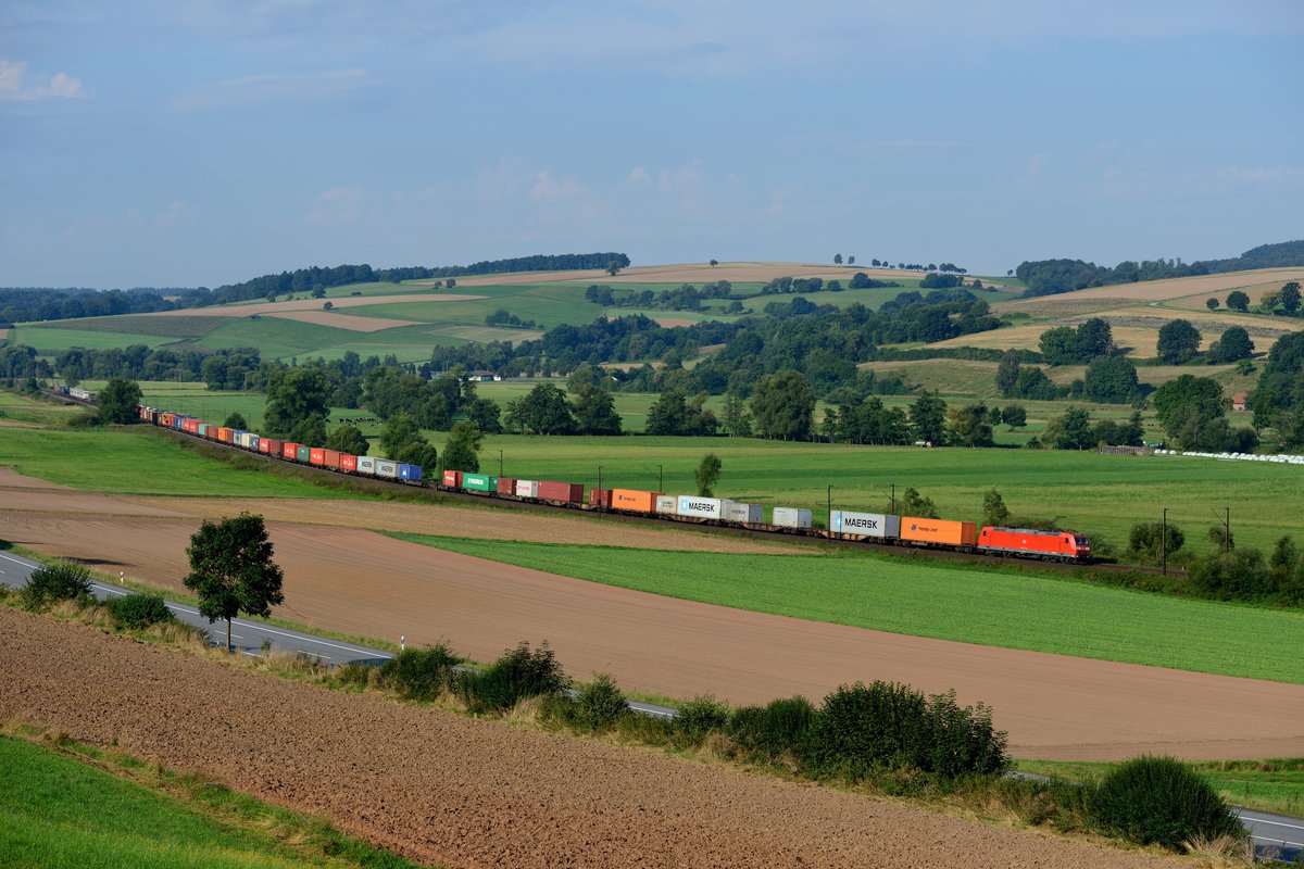 Bei Haunetal führt die Nord-Süd-Strecke durch die weitläufige Landschaft der Vorderrhön. Am 28. August 2016 konnte ich hier die 185 173 mit einem langen Containerzug aufnehmen. Im Bildhintergrund sieht man eine weitere 185 mit einem KLV südwärts fahrend.