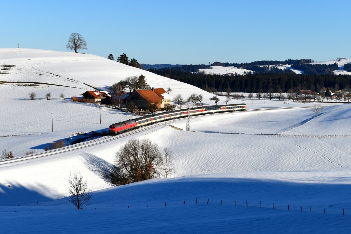 Bei Heimhofen im Westallgäu konnte ich am Morgen des 16. Februar 2019 den EC 196 auf seiner Fahrt nach Zürich HB aufnehmen. Es führten die Kemptner 218 420 vor der Mühldorfer 218 422. Auch wenn die Temperaturen schon wieder deutlich angestiegen waren, zeigte sich die Gegend um Oberstaufen noch tief verschneit.  