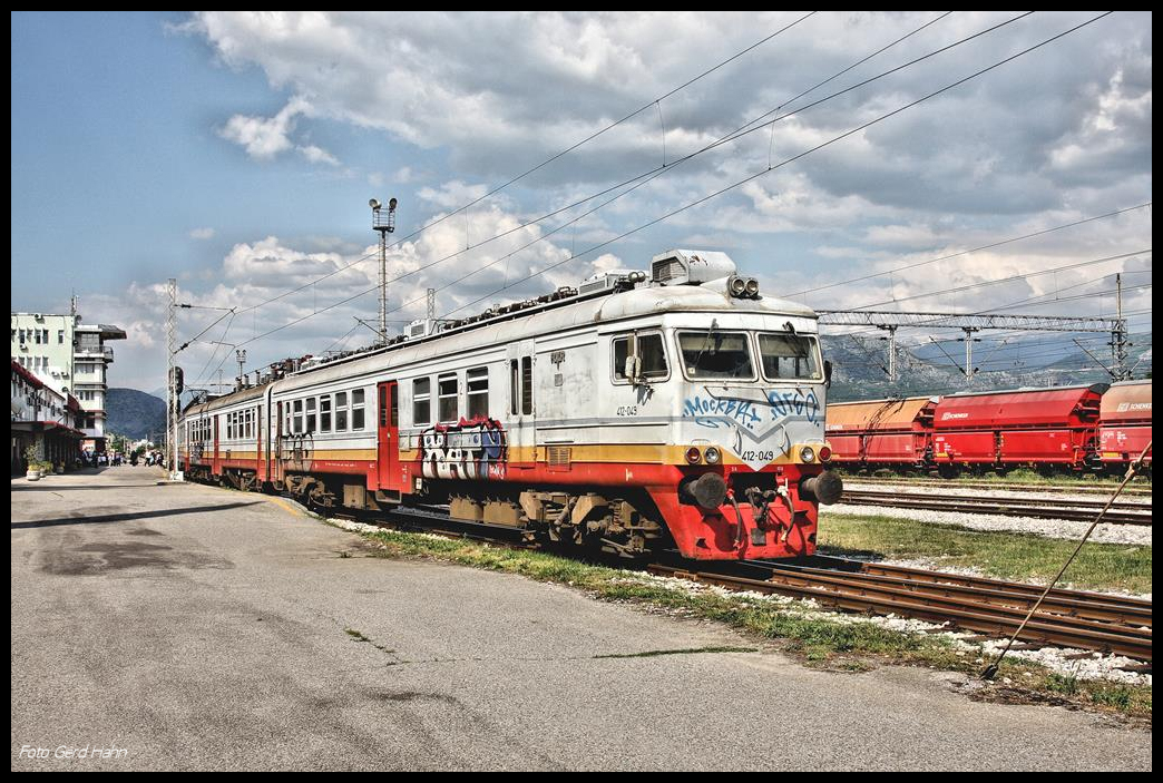 Bei herrlichem Fotolicht fährt hier der alte Elektrotriebwagen 412-049 vom Hausbahnsteig in Podgorica zum südlichsten Bahnhof des Landes nach BAR ab.