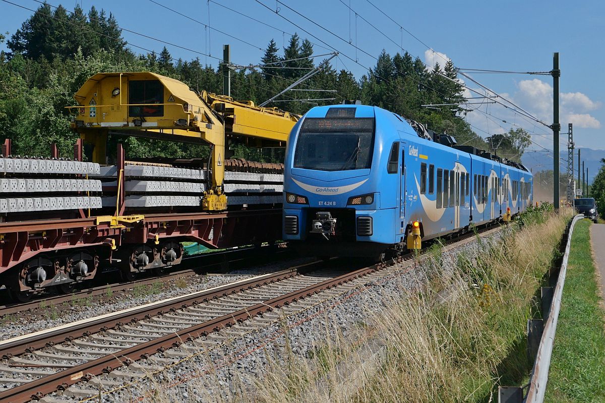 Bei Höhenreute fährt ET 4.24 als RE 96 / 78939, München - Lindau-Reutin, an den Schwellentransportwagen eines Gleisumbauzuges vorbei (09.07.2023)