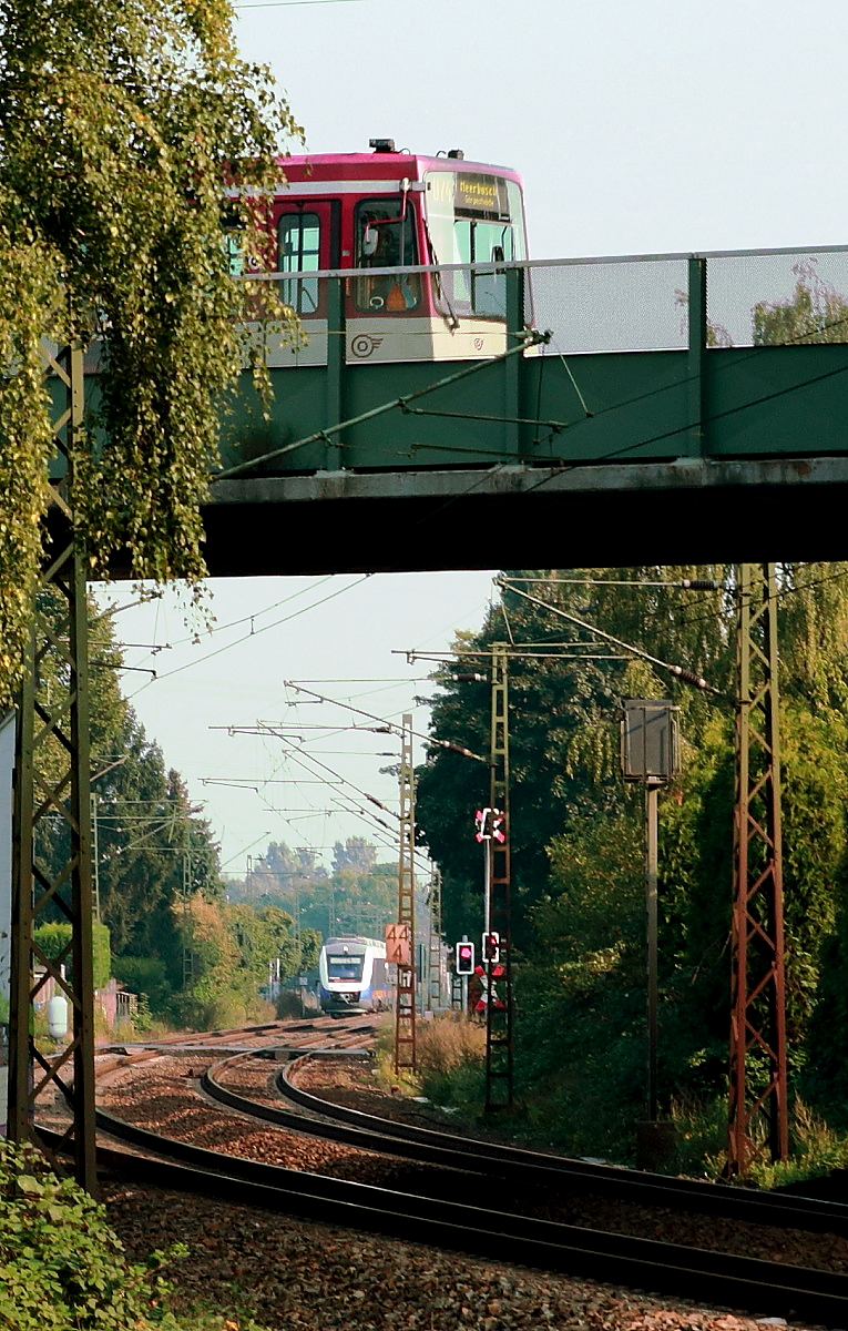 Bei Meerbusch-Osterath überquert die Stadtbahn von Krefeld nach Düsseldorf die DB-Strecke Krefeld-Düsseldorf/Neuss. Am 02.09.2017 fährt ein B 80 der Rheinbahn gerade über die Brücke, als sich im Hintergrund der VT 648 432 der Nordwestbahn auf dem Weg von Kleve nach Düsseldorf nähert.