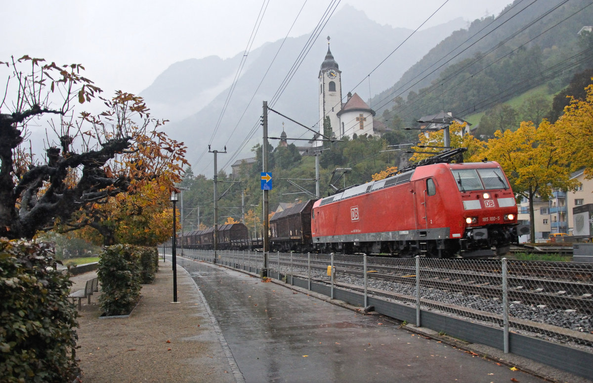Bei strömendem Regen fährt die 185 100-5 mit einem Güterzug bei Flüelen dem Gotthard entgegen. Auf dem kleinen Hügel oberhalb thront die katholische Kirche von Flüelen. 14.10.2016