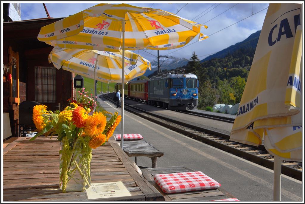 Bei einer Zwischenverpflegung im kleinsten Bahnhofbuffet der Schweiz lassen sich die Züge in Saas ganz bequem im Sitzen fotografieren. RE 1244 mit Ge 4/4 II 619  Samedan .(02.10.2015)