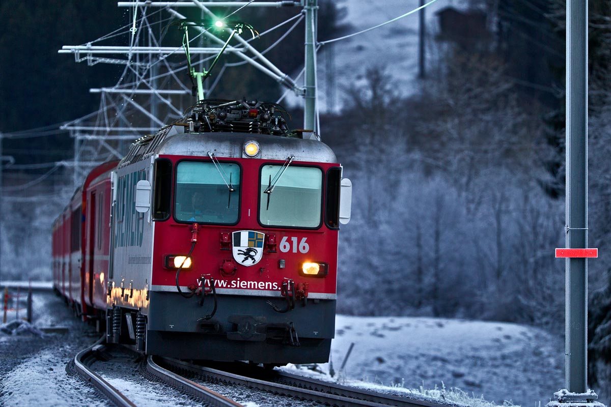 Beim Einnachten fährt die Ge 4/4 II 616 mit einem RE aus Landquart nach Disentis in Schnaus vorüber.Bild vom 16.12.2016