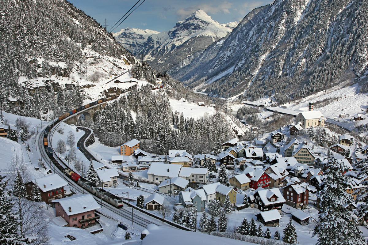 Bergaufwärts Re 10/10 bestehend aus den Loks Re 620 087-7 und der Re 420 347-7 kreuzen beim heute tiefverschneiten Dorf Wassen einen talwärts fahrenden Containerzug,geführt von der Crossrail Lok 185 590-8 und der Dispo-Lok Ewals Cargo 185 581-6 .Bild vom 2.2.2015