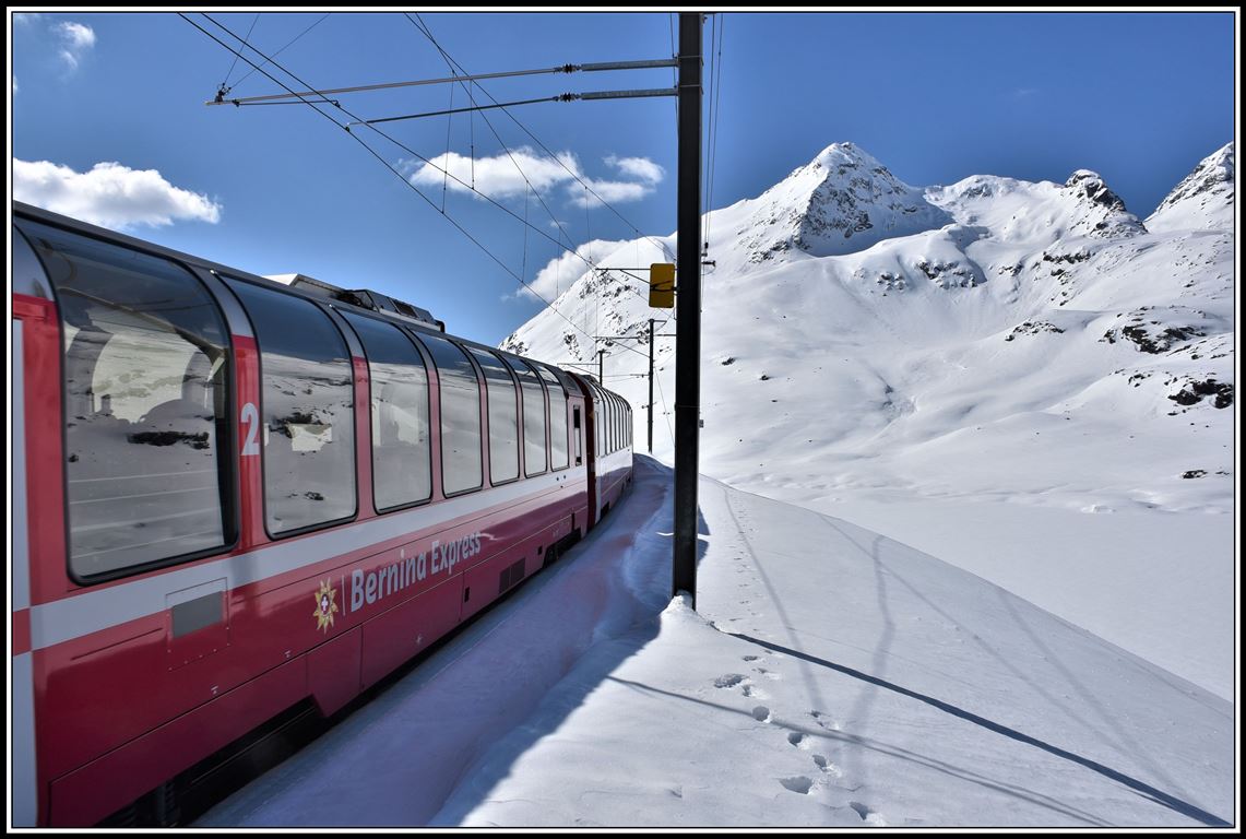 Bernina Express PE951 mit seinen Panoramawagen erreicht in Kürze Ospizio Bernina 2253m ü/M. Hinter dem Lago Bianco erhebt sich der Sassal Mason 3031m. (17.04.2019)