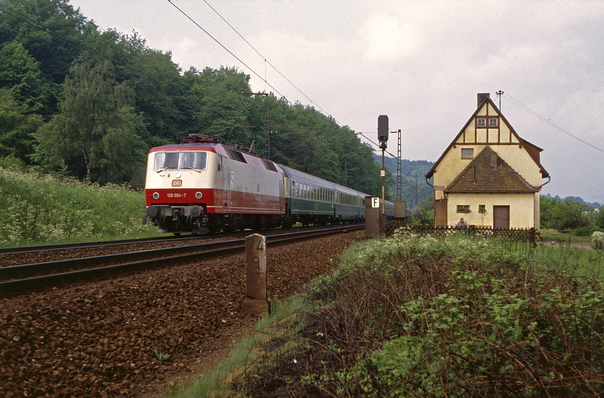 Besuche zu den Jubiläumsveranstaltungen 1985 in Nürnberg ließen sich immer gut mit ein paar Stunden an der Spessartrampe verbinden. Neben dem Schubbetrieb mit 194 und der ÖBB 1044 war ein IC mit 120.0 morgens eine begehrte  Zugabe . 120 004 trägt den damals weit verbreiteten Aufkleber  150 Jahre Deutsche Eisenbahnen . Aufnahme an der ehemaligen Blockstelle  Hain  am 24.5.1985.