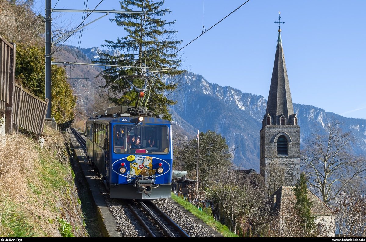 Bhe 4/8 302 mit Eigenwerbung für das  Marmottes Paradis  auf dem Rochers de Naye fährt am 6. März 2015 zwischen Toveyre und Montreux-Les Planches talwärts.