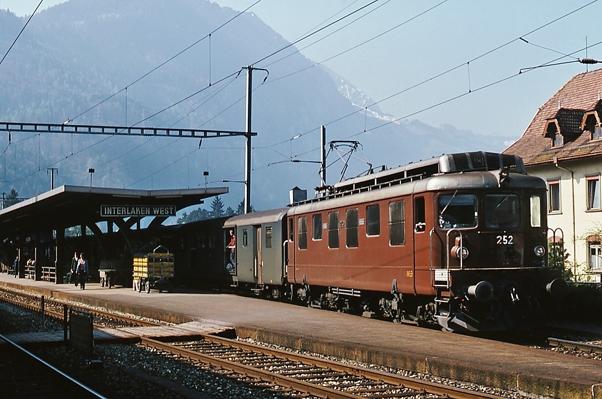 Bilder von der Lötschbergbahn im Mai 1981: Die im März 1945 in Dienst gestellte Ae 4/4 252 verläßt den Bahnhof Interlaken West in Richtung Interlaken Ost. Die Ae 4/4 der BLS war die die erste laufachslose Lokomotive mit Drehgestellen für den Einsatz im Schnellzugsverkehr und damit so etwas wie die Mutter aller modernen Elektrolokomotiven. Insgesamt stellte die BLS acht Lokomotiven in Dienst, von denen 4 später zu Doppelloks umgebaut wurden. Die Ae 4/4 252 wurde im März 1945 ausgeliefert und als erste der verbliebenen Ae 4/4 nach einem Brand 2002 ausrangiert.