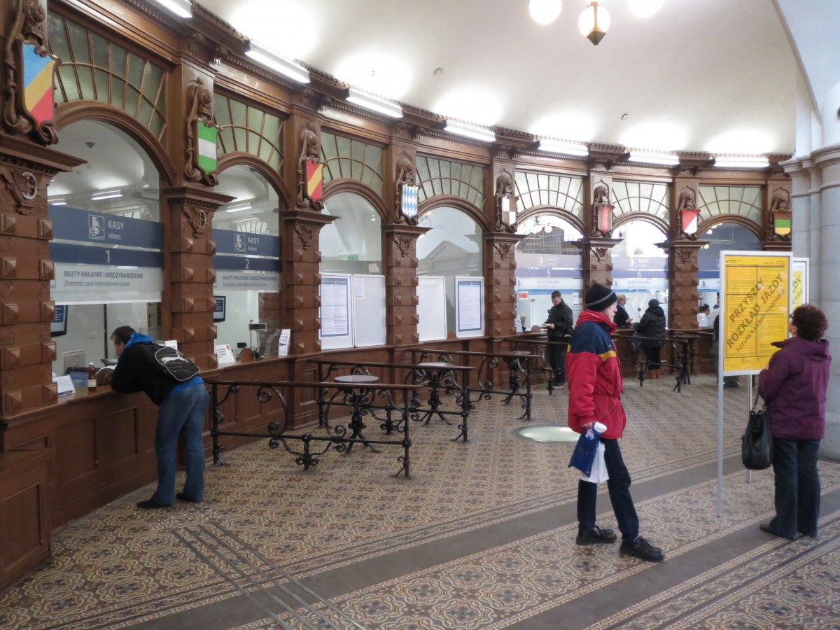 Blick am 14. Dezember 2014 in die Schalterhalle des an diesem Tag nach Renovierung wiedereingeweihten Bahnhofs Oppeln Hbf (Opole Glowne).

Bei den Wappen dürfte es sich nach heraldischer Deutung um die Landesfarben der Länder mit eigenen Länderbahnverwaltungen zur Zeit der Ersteinweihung des Bahnhofs 1899 handeln: 
Ganz in der Mitte natürlich als  heimisches  Wappen von Preußen. Die übrigen v.l.n.r.: Mecklenburg, Sachsen, Baden, Bayern, PREUSSEN, Württemberg, Oldenburg, rot-weiß schräg geteilt vermutlich stellvertretend hessisch für die Preußisch-Hessische Eisenbahngemeinschaft. Ganz rechts Schwarz-Grün-Gelb dürfte dann vermutlich für das Großherzogtums Sachsen-Weimar-Eisenach stehen. Denn mit der Ilmbahn von Weimar nach Kranichfeld und der Feldabahn in der Rhön betrieb Sachsen-Weimar-Eisenach immerhin zwei sehr kleine Bahnstrecken selbstständig, die man quasi als „Länderbahn“ begreifen könnte.
