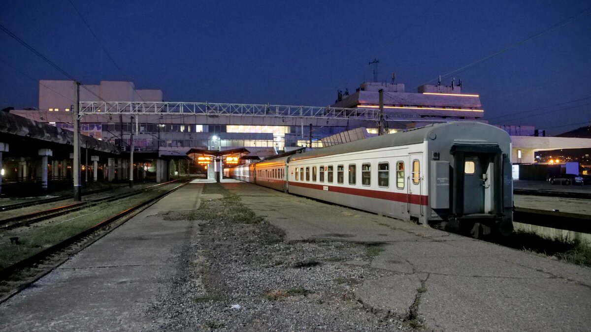 Blick auf den abendlichen Bahnhof Tbilisi Central (თბილისი ცენტრალი) mit abgestellten Personenwagen.
Aufgenommen im September 2023.