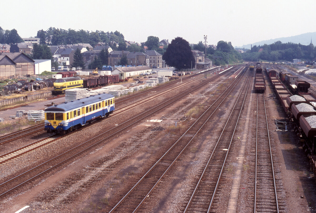 Blick auf die Bahnanlagen in Virton, wo NMBS 4505 von Gleis 2 abf�hrt als Zug L-5985 von Virton nach Libramont. Am Ladegleis links wartet NMBS 6287 auf Einsatz. Hinten links stehen noch 3 G-Wagen als Bahnhofswagen. Virton, 13.07.1999, Scan 7939.