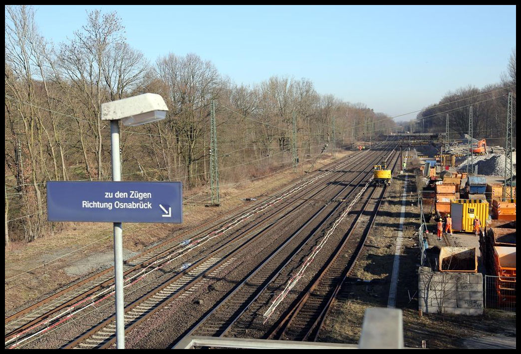 Blick auf den Bahnhof Natrup Hagen an der Rollbahn am 26.02.2019. Noch liegen die beiden verbliebenen Überholgleise. In Blickrichtung Osnabrück ist allerdings schon ein Zweiwegebagger mit dem Abbau des rechten Gleises beschäftigt.