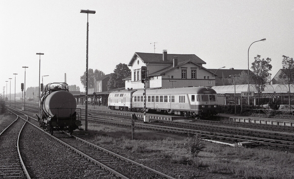 Blick auf den Bf Kleve, wo ein BDnf735, geschoben von DB 218 140-2, auf Abfahrt wartet als Zug E-3780 (Kleve - Nijmegen). 06.05.1990, 08.03u. Scanbild 7970, Ilford FP4.