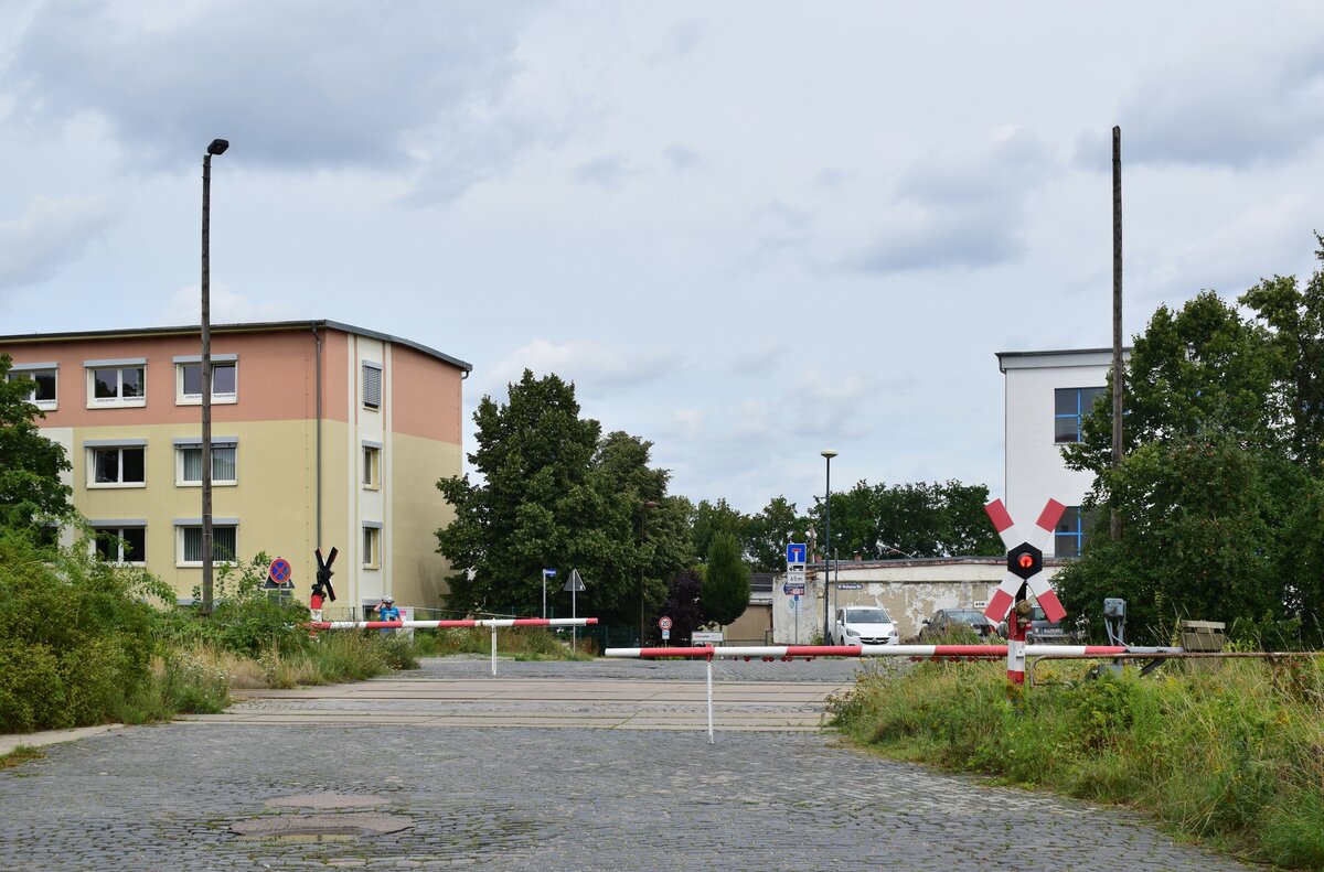 Blick auf dem BÜ Oststraße in Naumburg Ost im geschlossenen Zustand. Der Bahnübergang besitzt mechanische Halbschranken mit einer WSSB Lichtzeichenanlage. 

Naumburg 11.08.2021
