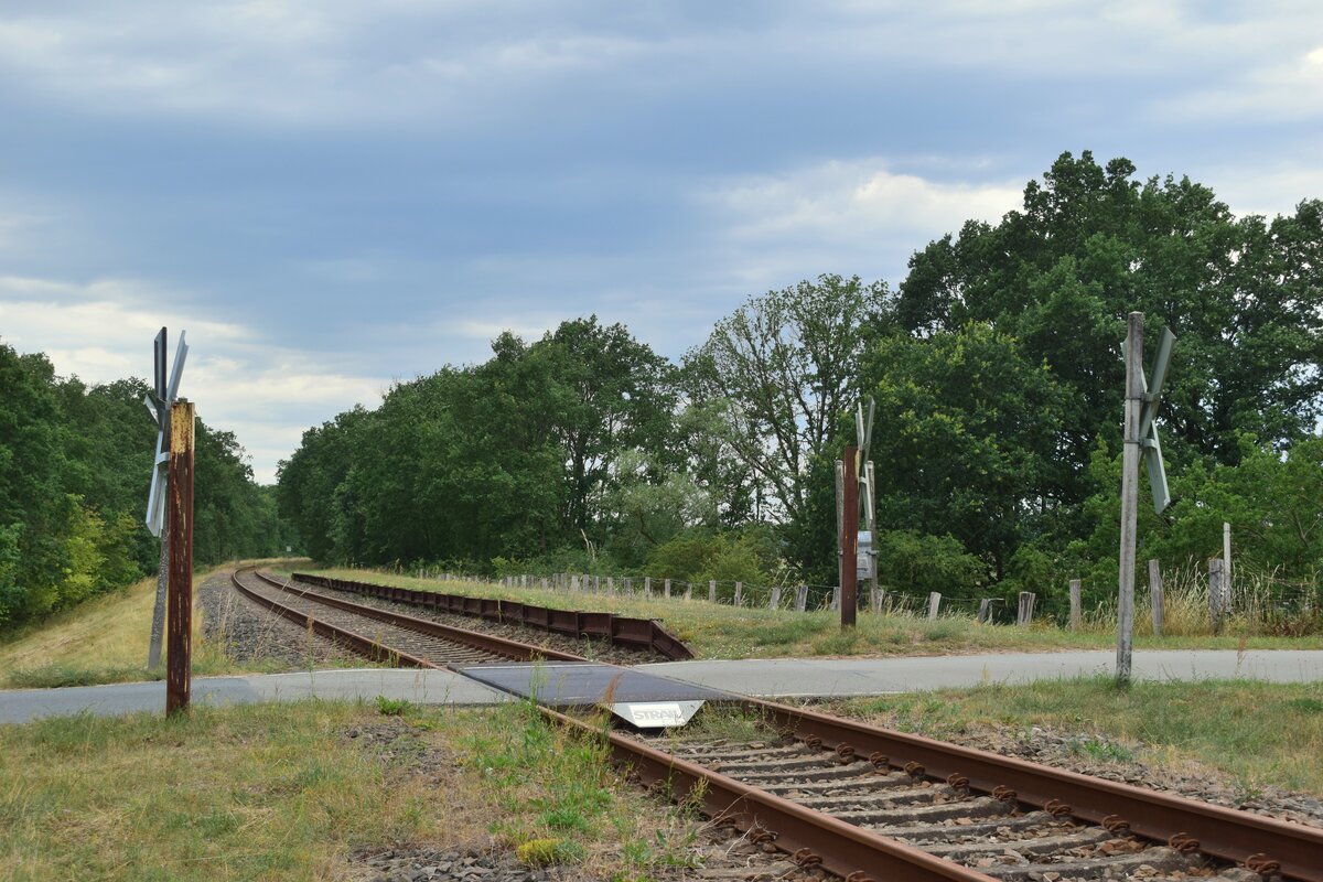 Blick auf den ehemaligen Haltepunkt Pisselberg. Aufgenommen von einem Trampelpfad auf einer Wiese neben dem Bahndamm.

Pisselberg 15.07.2023