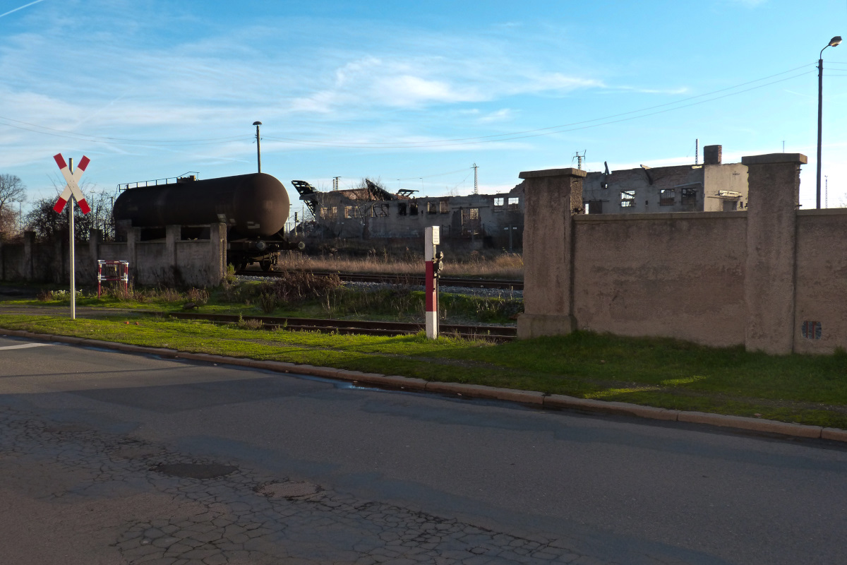 Blick auf ein völlig zerfallenes Gebäude des alten Güterbahnhofes von Nordhausen an dieser Stelle kreuzt auch der Gleisanschluß von Nordbrand Nordhausen (Schnaps und Industriealkohol) die Straße. An dem rot-weißen Pfosten befindet sich ein Knopf um das vorherige nicht existente DDR-Andereaskreuz aufleuchten zu lassen Nordhausen 26.12.2015