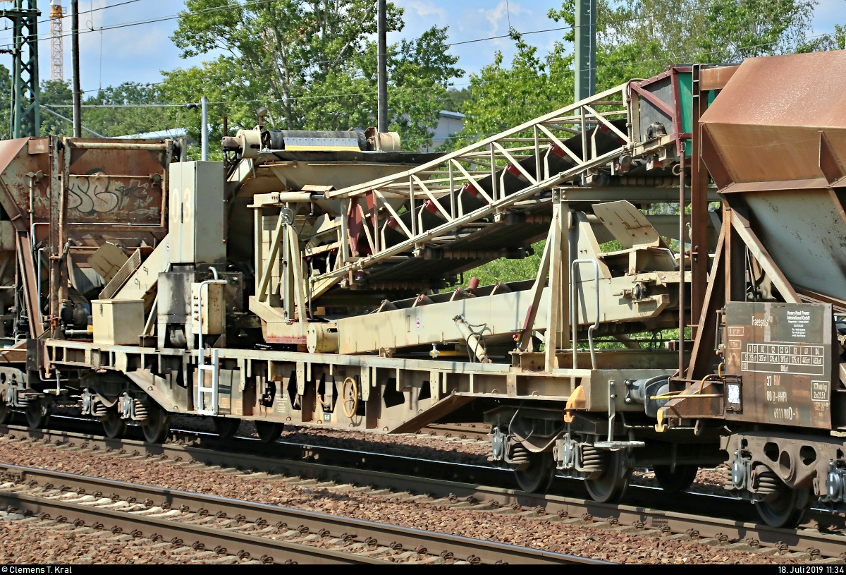 Blick auf den Entladewagen der Gattung  Uaks 351  (37 80 9351 000-6 D-HHPI) des aus mehreren, meist sechsteiligen, untereinander fest verbundenen Einheiten bestehenden Super Self Discharging Train (SSDT) der Heavy Haul Power International GmbH (HHPI), der in einem Schüttgutzug mit 266 005-8 (29006 | EMD JT42CWR) der Beacon Rail Leasing S.à r.l. eingereiht ist und den Bahnhof Berlin-Schönefeld Flughafen auf dem Berliner Außenring (BAR | 6126) Richtung Grünauer Kreuz durchfährt.
Aufgenommen am Ende des Bahnsteigs 3/5.
[18.7.2019 | 11:34 Uhr]