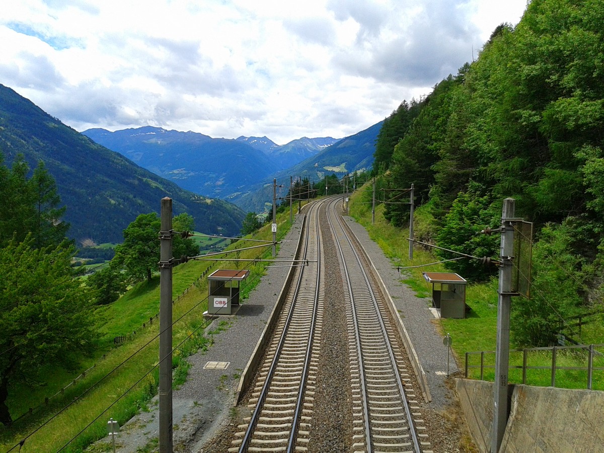 Blick auf die Haltestelle Oberfalkenstein am 21.6.2015. Auch hier stellt sich wie in Penk die Fragen ob hier noch Fahrgäste ein- oder aussteigen. In Oberfalkenstein wird auch nur noch am linken Bahnsteig gehalten, vermutlich deshalb da es auf den Bahnsteig rechts keinen richtigen Zugang gibt. Auf diesen Bahnsteig müsste man nämlich über eine steile Mauer einer Straßenüberführung (rechts im Bild) hinuntergehen. Auf dem linken Bahnsteig wurde der Zugang ganz simpel gelöst. Hier wurde einfach ein Erdsteig getrampelt. Zudem besitzt diese Haltestelle auch keine Lautsprecheranlagen. Das heißt wenn ein Zug ausfällt wird man nicht informiert und wenn kurzfristig ein SEV eingeführt würde, müsste man auch  nur  schnell ca. 3,5 Kilometer bis nach Obervellach zur Bushaltestelle gehen.