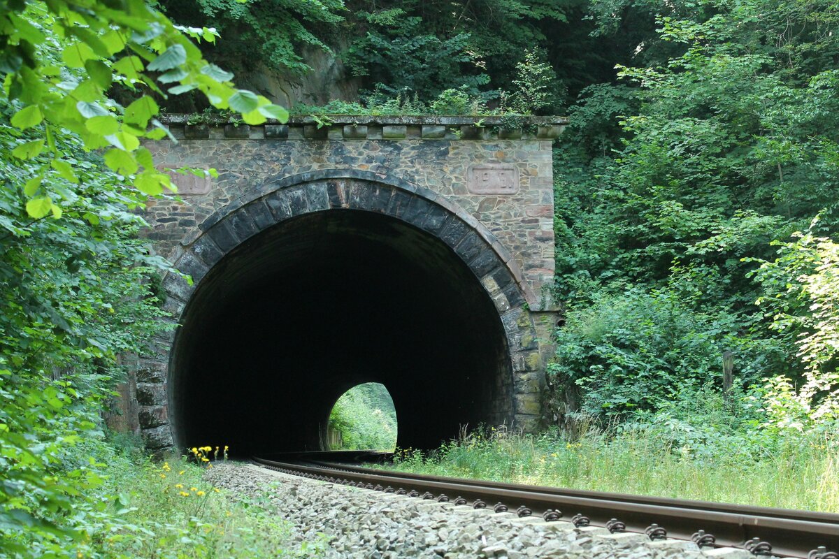 Blick auf das Ost-Portal des Harrasmühlentunnels zwischen Oppurg und Neunhofen auf der Bahnlinie (Leipzig)-Gera-Saalfeld (KBS 555). Der 117m lange und zugleich einzige Tunnel der Strecke wurde 1871 im Zuge des Bahnlinienbaus vorerst eingleisig errichtet und war ab 1915 zweigleisig ausgelegt. Hiervon zeugen die beiden Jahreszahlen am Tunnelportal. Im Zuge von Reparationsleistungen an die Sowjetunion wurde das zweite Gleis 1946 demontiert. Die Strecke ist bis heute eingleisig geblieben.