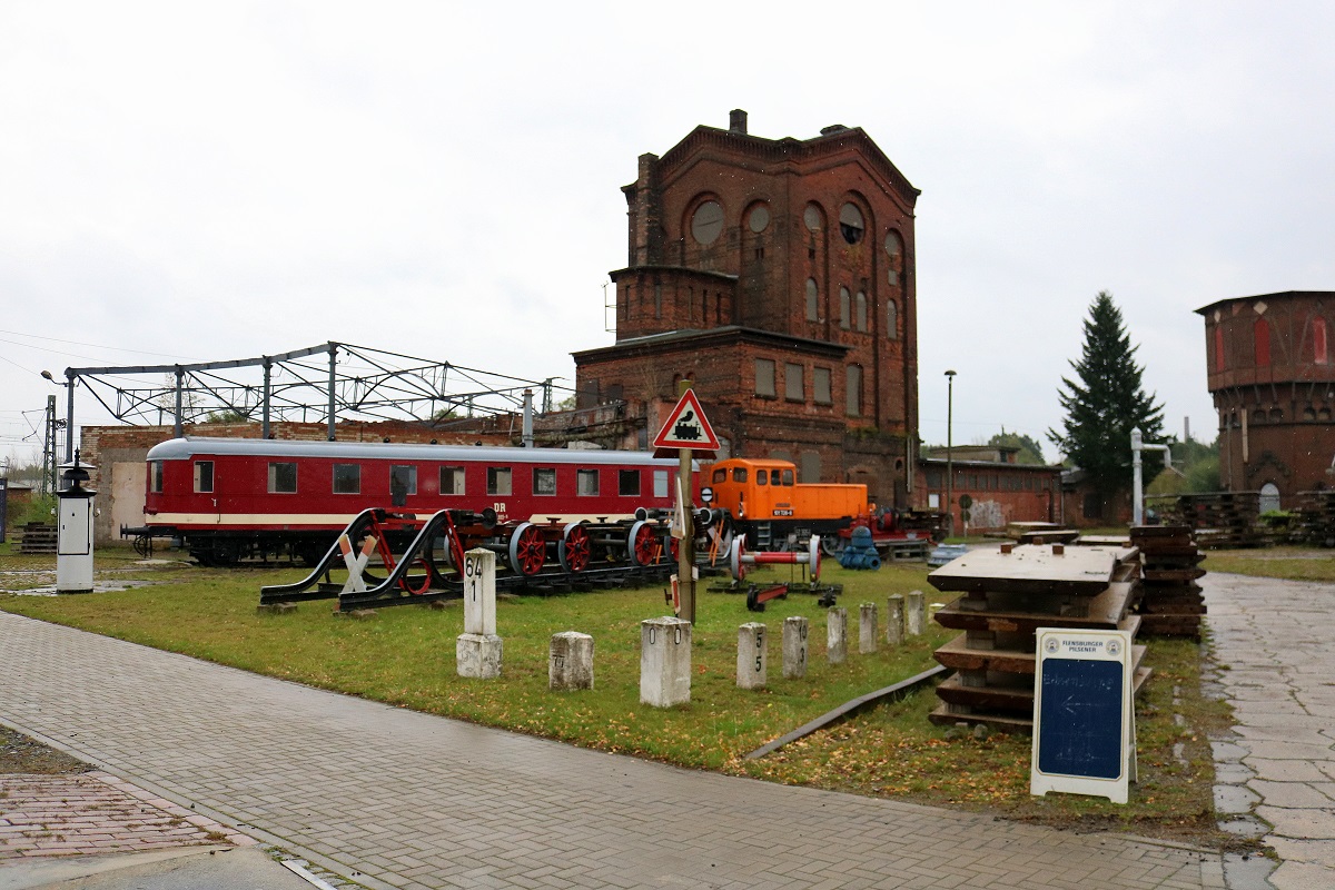 Blick auf eine Reihe von Achsen, Kilometersteinen und Bahnschildern, die auf dem Gelände des Historischen Lokschuppens Wittenberge anlässlich der Herbstdampftage stehen. Im Hintergrund sind Wagen 197 805-5 und 101 726-8 (BR 311) zu sehen. [7.10.2017 | 14:56 Uhr]