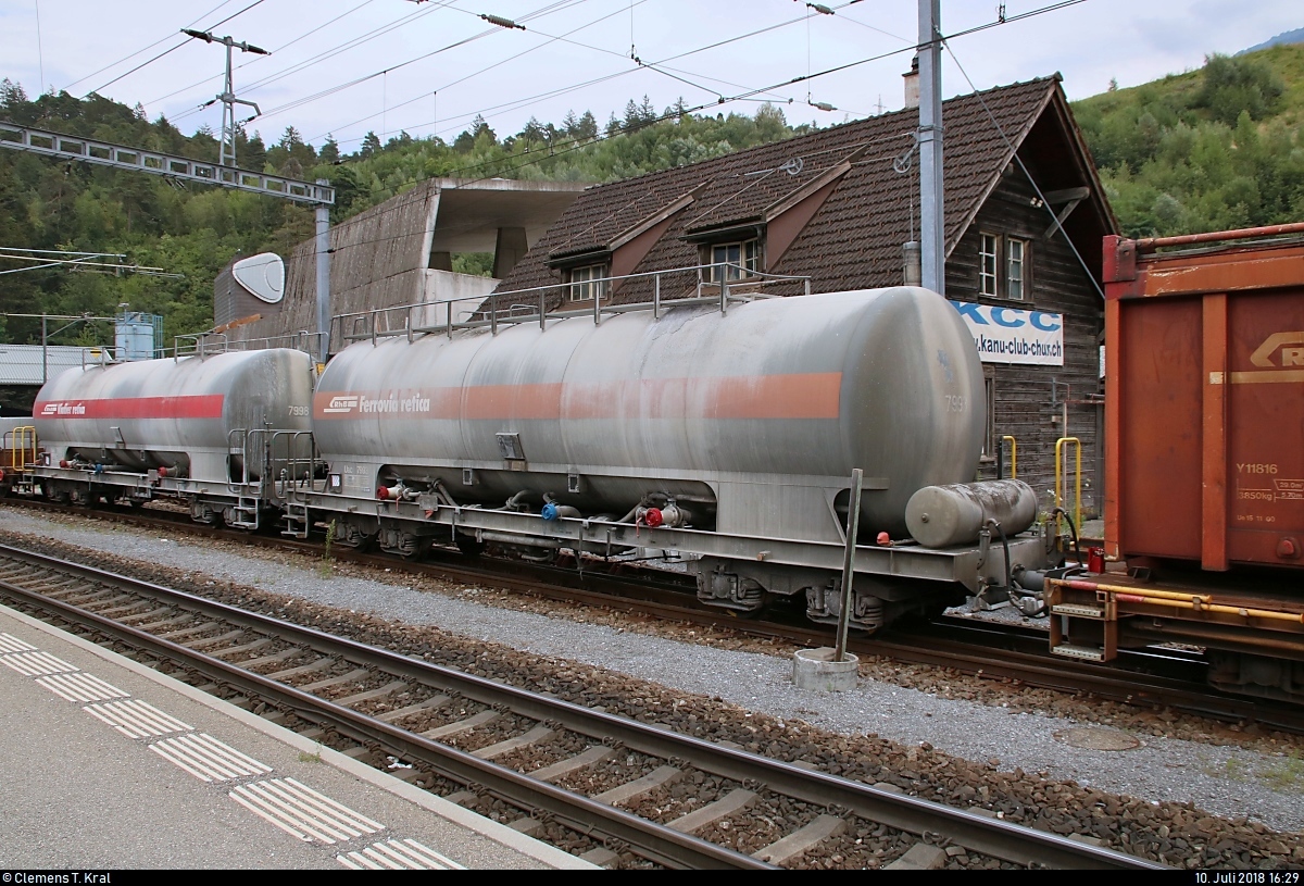 Blick auf zwei Kesselwagen der Gattung  Uac  (7998 und 7993) der Rhätischen Bahn (RhB), die in einem gemischten Gz mit Ge 6/6 II 703  St. Moritz  der Rhätischen Bahn (RhB) eingereiht sind und im Bahnhof Reichenau-Tamins (CH) stehen.
[10.7.2018 | 16:29 Uhr]
