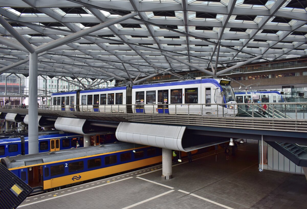 Blick in den Bahnhof Den Haag Central. Unten stehen die Züge der NS und oben fahren die Straßenbahnen. Durch das sehr futuristische Dach wird die Halle sehr lichtdurchflutet.

Den Haag 25.09.2021