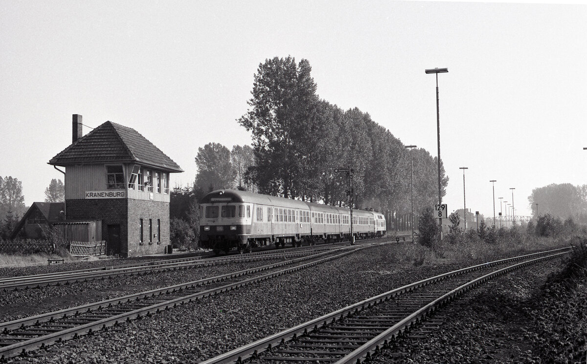 Blick vom Bahnübergang auf den Bf Kranenburg. Wendezug geschoben vom DB 218 144-4 hat Ausfahrt. Zug E-3774 (Köln Hbf - Nijmegen) am 03.10.1987. Links sieht man Stellwerk  Kw . Scanbild 94620, Ilford FP4.