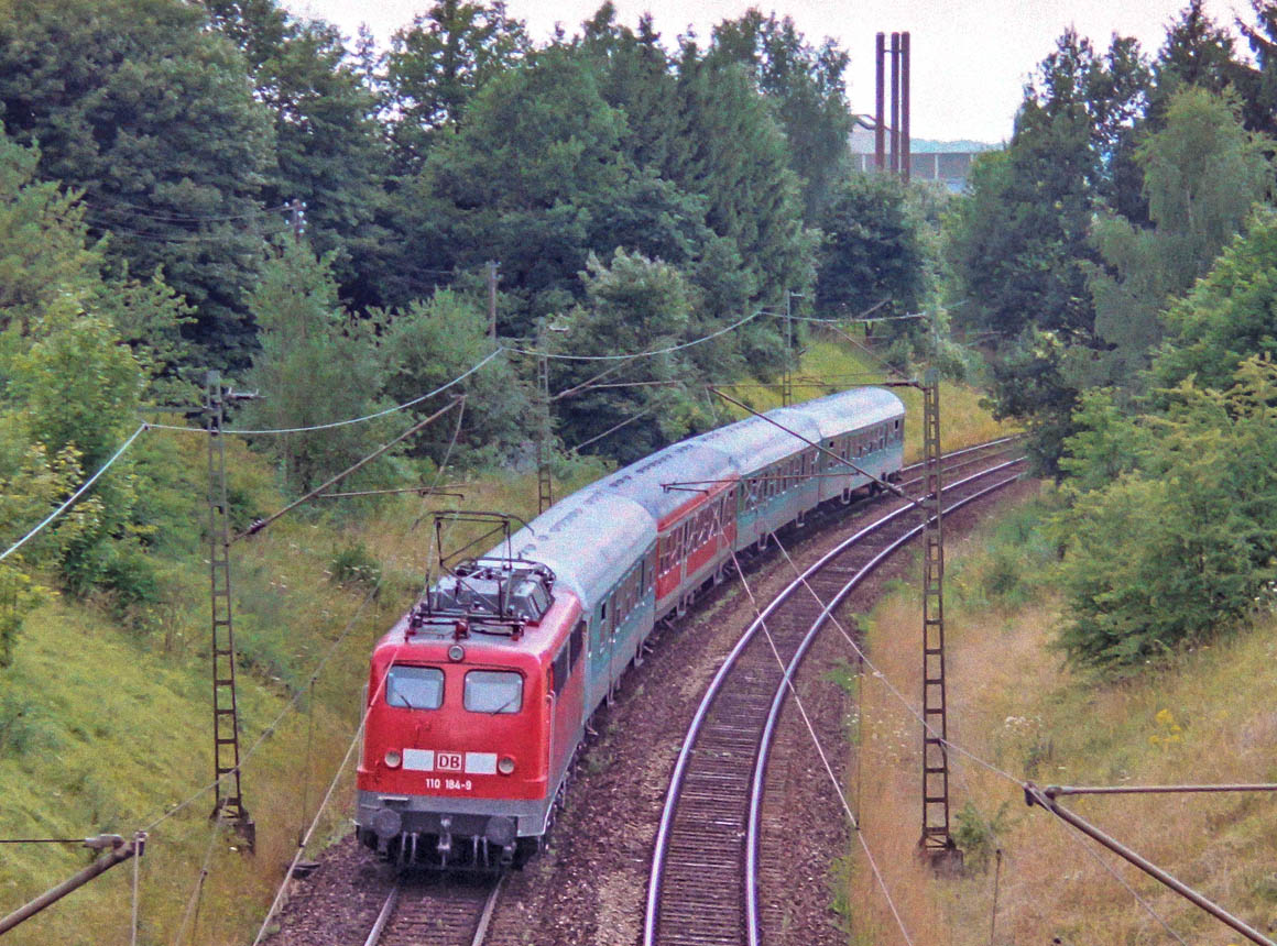 Blick von der Brücke der Bundesstraße 290 nach Westen auf 110 184 mit einem RE nach Nürnberg.  1,5 km ab Crailsheim liegt das Gleis der Taubertalbahn etwa 50 Meter entfernt rechts vom Bildrand.