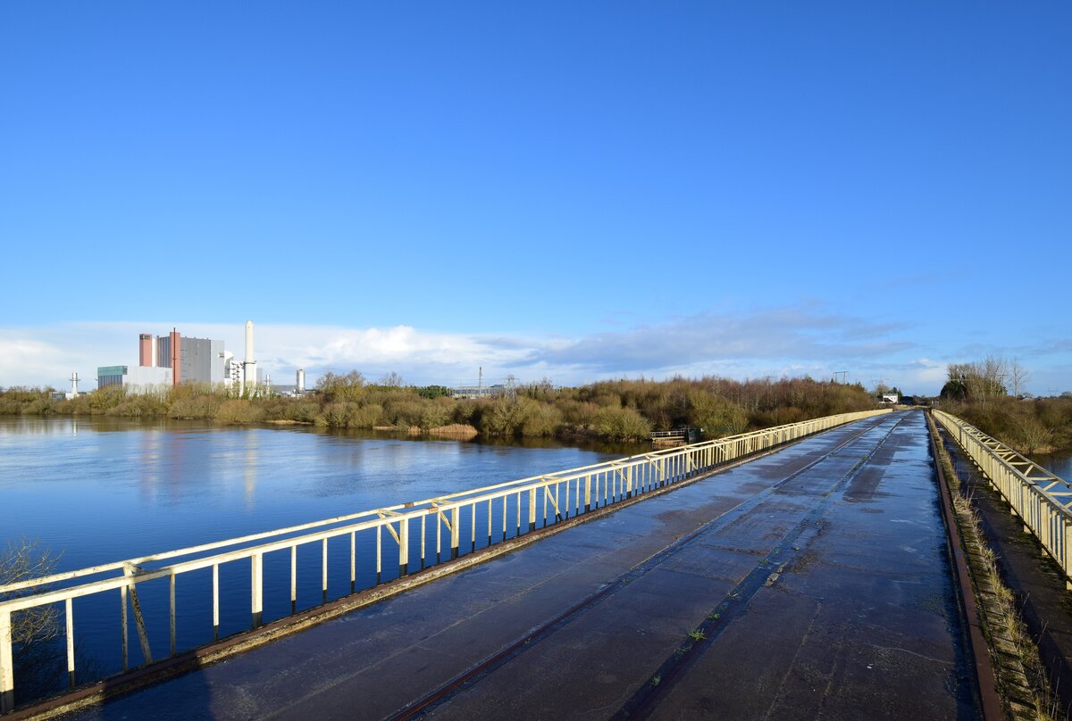 Blick von einer Brücke über den Fluss Shannon auf das 2020 stillgelegte Torfkraftwerk West Offaly. Mit der Stillegung der letzten Torfkraftwerke in Irland endete auch der Torfabbau in Irland. Die Clonmacnoise and West Offaly Railway welche hier tätig war hatte ein Gleisnetz von etwa 9km Länge und bot bis 2008 sogar Touristenverkehr an. Heute findet man überall noch die alten Gleise und Brücken der ehemaligen Torfbahn. 

Shannonbridge 07.01.2025