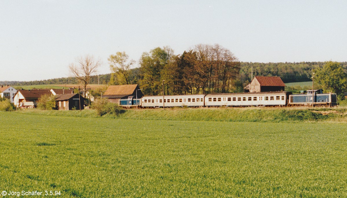 Blick von der Bundesstraße B 279 nach Osten auf 211 056 an der Spitze ihres „Sandwichzuges“ im Bahnhof Rentweinsdorf. Der Bahnhof liegt im Ortsteil Treinfeld, vom Hauptort auf der anderen Seite der Weisach etwa 1 km entfernt. (3.5.94)