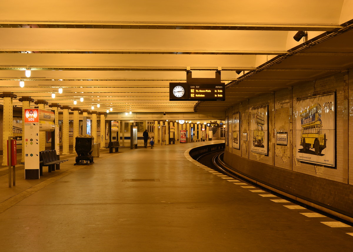 Blick durch den am 1.Juli 1913 eröffneten U-Bahnhof Klosterstraße. Dieser Bahnhof zeigt an den Wänden nicht nur die Entwicklung von U-Bahn, Straßenbahnen und Bussen sondern hat auch noch viel Geschichte zu verbergen.

Geschichte

Der U-Bahnhof Klosterstraße befindet sich etwa auf Höhe der Parochialstraße. Auffällig ist die relativ große Breite des Bahnsteigs sowie die versetzte Stützenreihe. Ebenfalls auffällig sind die zwei in den Boden eingelassenen Granit­bänder, die sich in der Mitte längs des Bahnsteigs hinziehen. Im eigentlichen Sinne handelt es sich hierbei um zwei Bahnsteige, die zu einem großen zusammengefasst wurden. Die Granitbänder stellen die ehemals geplanten Bahnsteigkanten dar.

Der Bahnhof wurde nach Plänen von Alfred Grenander errichtet und am 1. Juli 1913 im Zuge der Verlängerung der Centrums-Linie eröffnet. Geplant war, neben der noch im gleichen Jahr eröffneten Hochbahn in der Schönhauser Allee, eine Strecke zur Frankfurter Allee zu bauen. Diese sollte im Bahnhof Klosterstraße von der Stammstrecke abzweigen und diese anschließend am Bahnhof Alexanderplatz in einem Turmbahnhof kreuzen. Die Pläne wurden später zugunsten einer Großprofillinie (heutige Linie U5) aufgegeben.

Vorgesehen war ein Bahnhof mit zwei Bahnsteigen und drei Bahnsteigkanten. Das mittlere Gleis sollte die Züge von der Frankfurter Allee kommend aufnehmen; diese sollten danach in die Stammstrecke eingefädelt werden. Der westliche Bahnsteig sollte die Züge von der Schönhauser Allee aus kommend aufnehmen. Der östliche Bahnsteig, auf dem sich die Stützenreihe befindet, sollte schließlich alle Züge, die vom Potsdamer Platz kommen, aufnehmen; die Linien hätten sich erst nach dem Bahnhof verzweigt. Im Falle einer Umsetzung der Pläne wäre der östliche Bahnsteig als kleinerer der beiden mit einer Breite von nicht einmal drei Metern ausgefallen.

Im Zugangsbereich ist der Bahnhof mit stilisierten Palmen aus orangefarbenen, blauen und weißen glasierten Fliesen geschmückt. Die Darstellungen entstanden mithilfe von Ziegeln in gleicher Weise wie für das Ischtartor im Pergamonmuseum, weil bei dessen Aufbau einige Fliesen mehr angefertigt worden waren.

Der Bahnhof wurde 1975 in die Berliner Bezirksdenkmalliste aufgenommen. Zwischen 1984 und 1986 führte das Wohnungsbaukombinat Karl-Marx-Stadt eine aufwendige Sanierung im Zuge der Vorbereitung zur 750-Jahr-Feier Berlins im Jahr 1987 durch. Dabei wurden wesentliche Schäden, die noch aus Kriegstagen stammten, beseitigt und der Bahnhof zu einem „erfahrbaren“ Museum umgestaltet. Die Werbetafeln, die zu DDR-Zeiten nicht benötigt wurden, boten Platz für insgesamt 22 Emailletafeln aus dem Werk Beutha, die die Entwicklung des Berliner Nahverkehrs anhand der jeweiligen Fahrzeuge darstellen. Zusätzlich wurde der vordere Teil des Triebwagens 12 der Schöneberger Untergrundbahn aus dem Jahr 1910 in seinen Ursprungszustand zurückversetzt und im November 1985 am nördlichen Ende des Bahnsteigs zwischen den beiden Treppen platziert. Der Wagen diente vorher zu Überführungsfahrten (Wagennummer 710 008 ehemals 359) zwischen den beiden Ost-Berliner U-Bahn-Linien, wurde 1982 nach einem Unfall ausgemustert und soll an seiner jetzigen Position die Einfahrt eines Kleinprofilzuges von der Frankfurter Allee kommend symbolisieren. Seine Zukunft ist ungewiss, da an dieser Stelle bis 2020 ein Aufzug eingebaut werden soll. Am südlichen Ende des Bahnsteigs wurde hinter Glas ein mechanisches Stellwerk der Erstausstattung der Hochbahn aufgebaut.

Nach der politischen Wende änderte sich relativ wenig am Bahnhof selbst. Erste merkliche Änderung waren unter anderem neue Zugziele im Westen Berlins, da 1993 die ehemalige Linie A zur neuen Linie U2 zusammenschloss. Seitdem können Fahrgäste vom Bahnhof Klosterstraße beispielsweise das KaDeWe am Wittenbergplatz oder den Zoologischen Garten direkt mit der U-Bahn erreichen.

Die Realisierung eines bisher nicht vorhandenen behindertengerechten Zugangs ist laut der vereinbarten Prioritätenliste zwischen BVG, Senat und Behindertenverbänden erst nach 2016 geplant. Eine Ausstattung mit Blindenleitstreifen ist unter Umständen bereits vorher zu erwarten. 

Berlin Mitte 03.01.2018


Seite „U-Bahnhof Klosterstraße“. In: Wikipedia, Die freie Enzyklopädie. Bearbeitungsstand: 27. November 2017, 21:54 UTC. URL: https://de.wikipedia.org/w/index.php?title=U-Bahnhof_Klosterstra%C3%9Fe&oldid=171456554