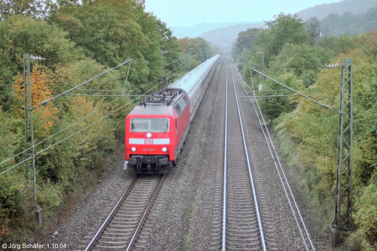 Blick von der Fußgängerbrücke nach Süden: 120 133 fuhr am 1.10.04 mit einem InterCity Richtung Würzburg durch Burgbernheim-Wildbad. Das Empfangsgebäude versteckt sich rechts zwischen den Bäumen neben dem km-Schild 80,2.  