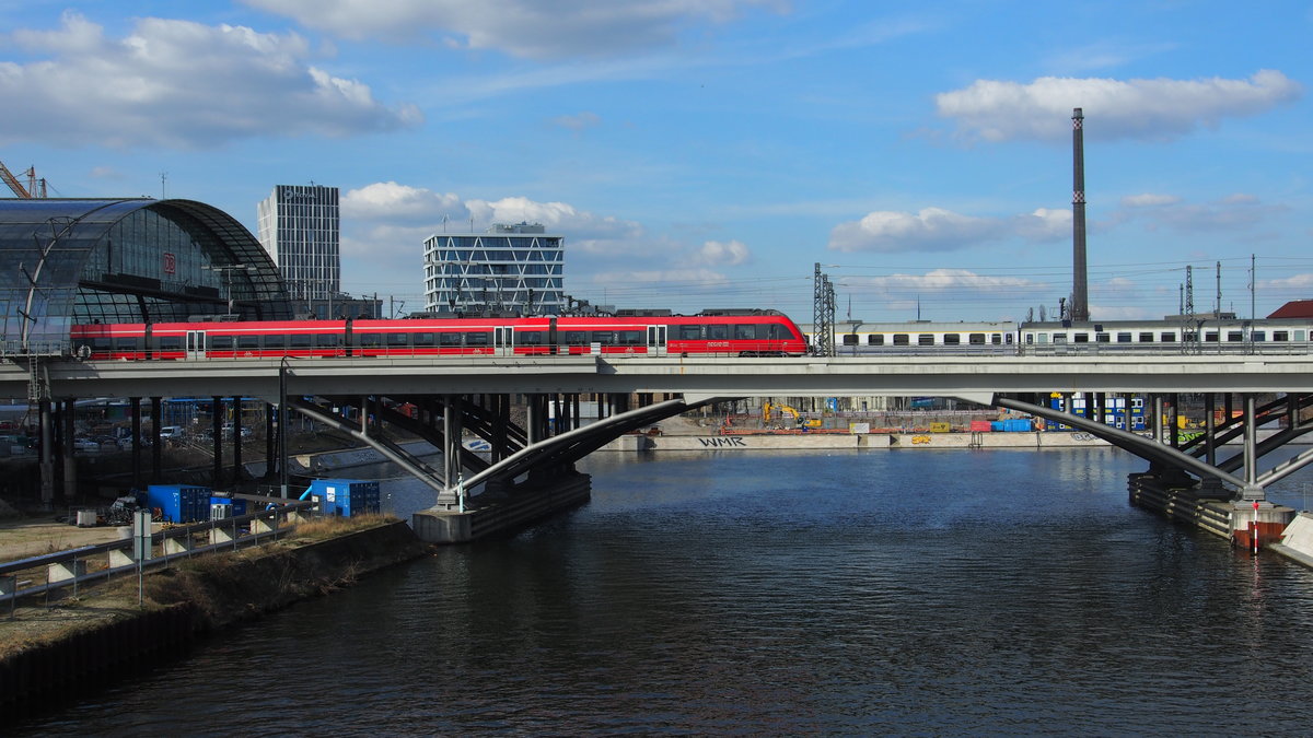 Blick von der  Hugo-Preuß-Brücke  nach Norden.
Die Spree überqueren ein unbekannter Talent2 als RE 3724 nach Wünstorf-Waldstadt und dahinter fährt in den Berliner HBF EC 44 aus Warszawa Wschodnia.

Berlin, der 26.03.2017