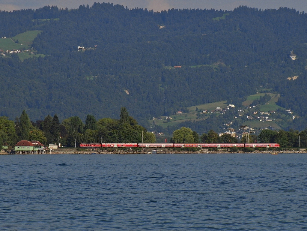 Blick von Lindau-Bad Schachen auf das Badehaus von Lindau-Aeschach und den Bodenseebahndamm, auf dem gerade IRE 4214 auf der Fahrt nach Ulm den Startbahnhof Lindau verlassen hat (17.08.2013).
