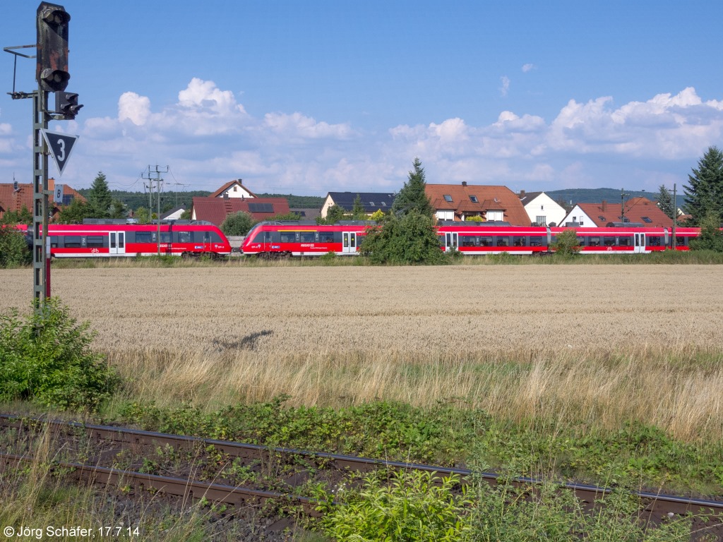 Blick nach Osten auf Strullendorf mit einer S-Bahn nach Bamberg am 17.7.14. Der Bahnhof liegt links vom Bild, im Vordergrund das Einfahrsignal der Nebenbahn aus Schlüsselfeld. 