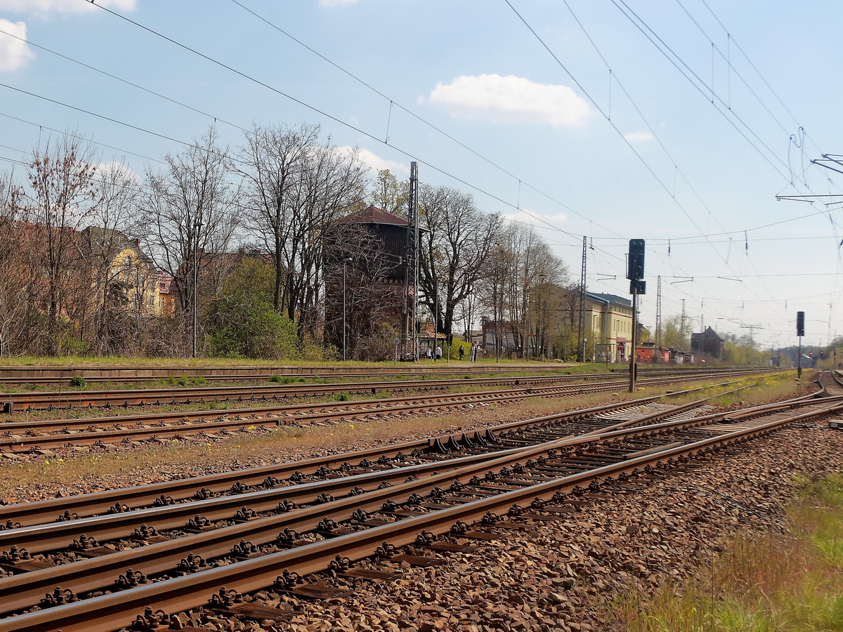 Blick von der Straße An den Wulzen zum Gleis 1 mit dem Bahnhofsgebäude und dem Bahnwasserturm des Bahnhofs Zossen am 28. April 2021.