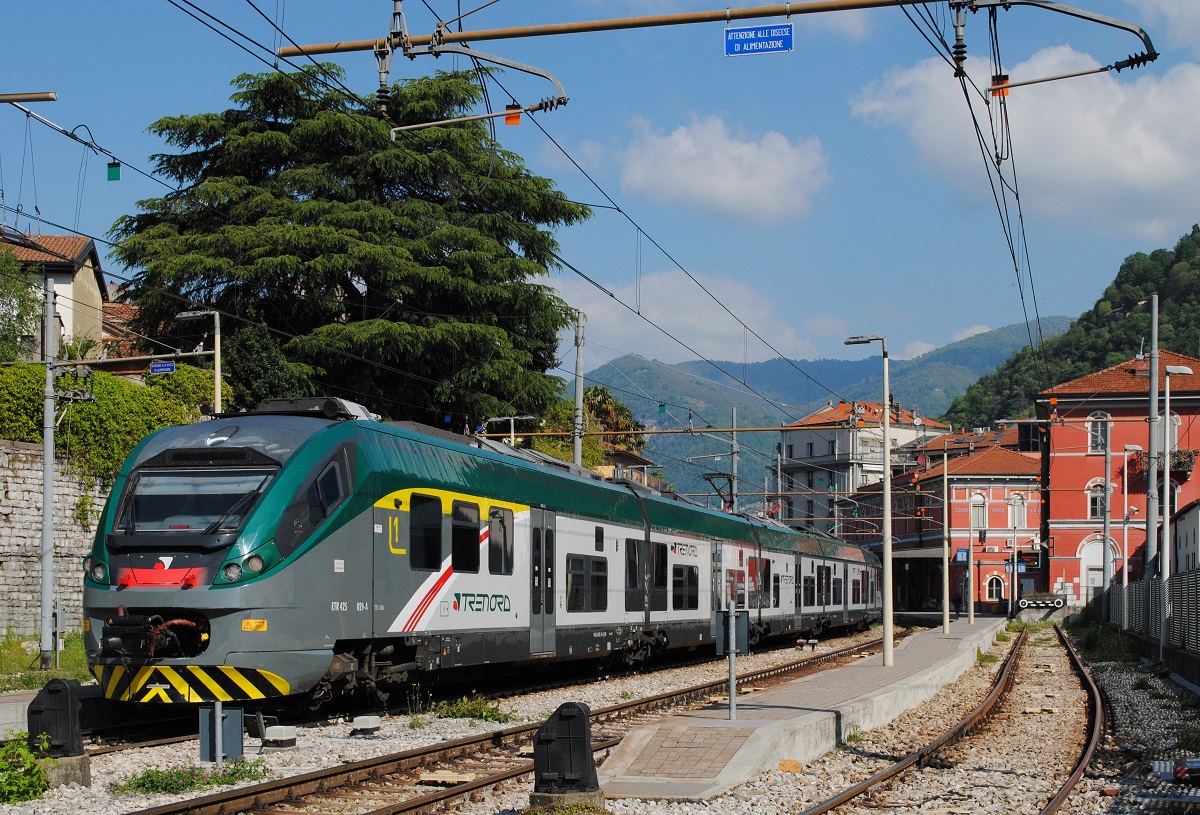 Blick von der Stra�e �ber den Zaun: ETR 425 029 der Trenord wartet als R17 im Bahnhof Como - Lago auf die Abfahrt nach Milano - Cadorna. (23.04.2026)