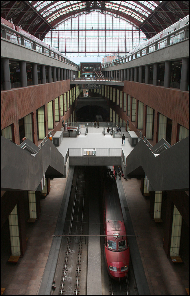 Blick in die Tiefe eines Bahnhofes -

Der Bahnhof Antwerpen Centraal ist auch hochmodern. Am 23.06.2007 ging der umgebaute Bahnhof in Betrieb. Die Züge fahren heute auf drei Ebenen mit insgesamt 14 Gleisen ab. Blick in die -2 Ebene, wo sich die vier Durchgangsgleise befinden. Die anderen zehn Gleise enden weiterhin im Bahnhof, davon sechs Gleise oben und vier Gleise in der -1 Ebene, rechts und links neben der Öffnung. Über der modernen Anlage befindet sich nach wie vor das alte Bahnsteigdach. Das alte Empfangsgebäude wird in einem zweigleisigen Tunnel unterfahren.

Der Bahnhof ist Teil der Hochgeschwindigkeitsstrecke (Brüssel -) Antwerpen - Rotterdam - Amsterdam.

18.06.2016 (M)