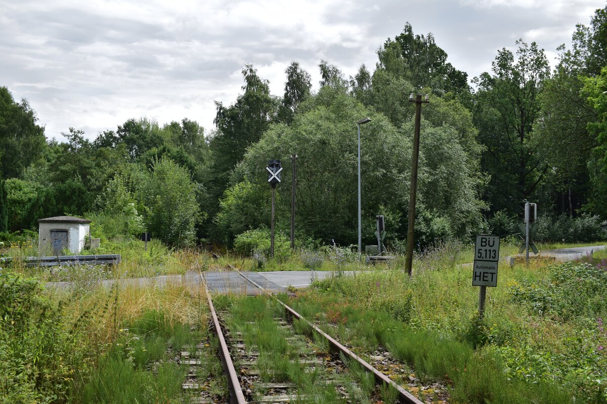 Blick von Triptis kommend auf den Bahnübergang Kilometer 5,113 auf der L 1087 zwischen Gütterlitz und Auma. In den 90er Jahren oder Anfang der 2000er wurden noch viele Bahnübergänge entlang der Strecke nach Unterlemnitz modernsiert und teilweise mit Automatik HET ausgestattet. Im Hintergrund sieht man noch das Lichtvorsignal von Auma. Der Personenverkehr wurde am 24. Mai 1998 eingestellt und der Güterverkehr weinge Monate später Ende 1998. Seit dem 1.1.2005 ist die Strecke offiziell stillgelegt.

Auma 31.07.2023