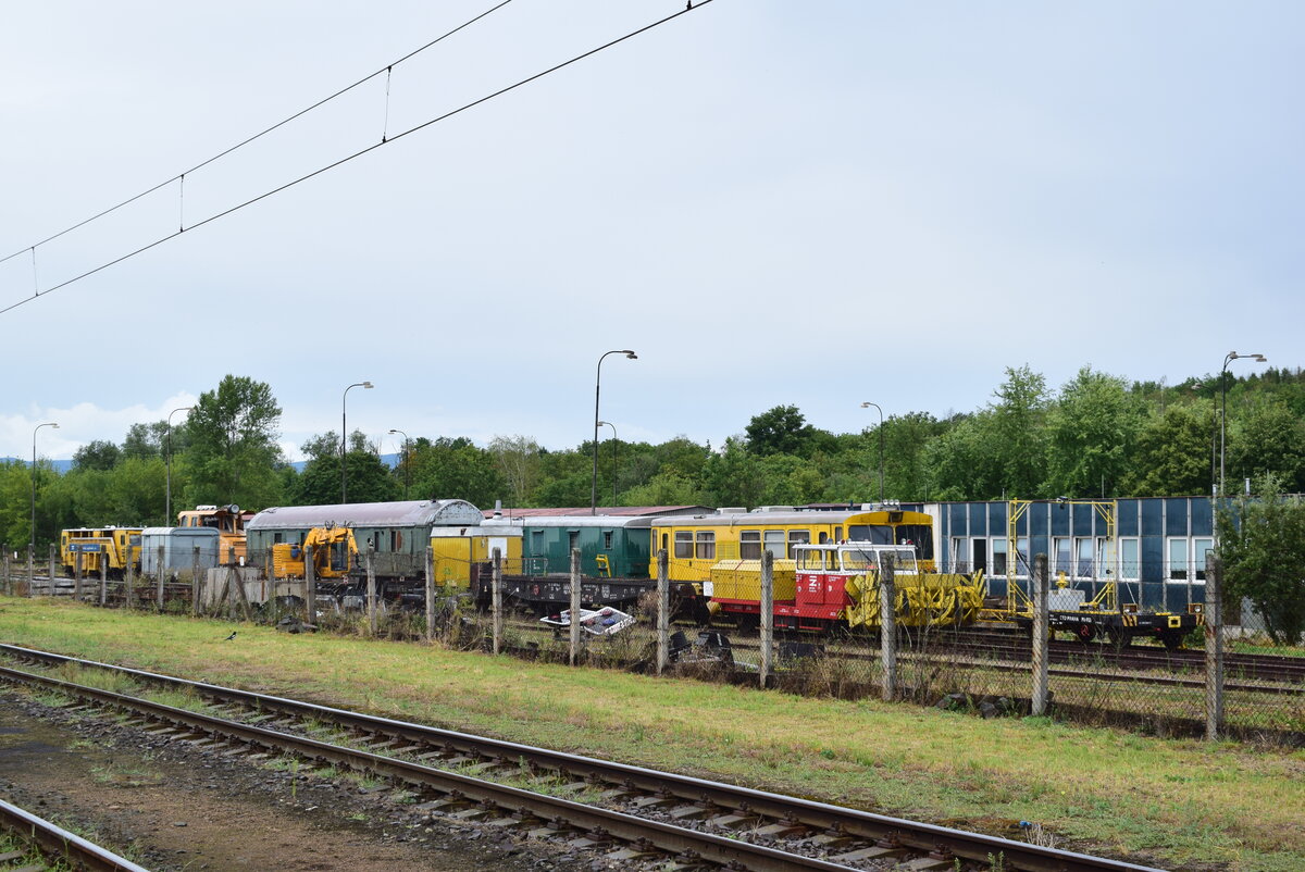 Blick über den Gleisbauhof von Most. Hier stehen unter anderem eine Stopfmaschine, ein Instandhaltungsfahrzeug in Gelb sowie ein Kleinfahrzeug mit Schneefräse.

Most 29.07.2023