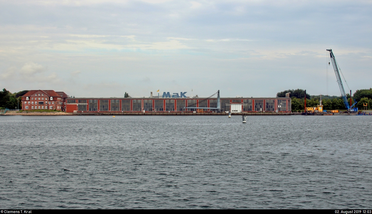 Blick während einer Hafenrundfahrt auf das Gebäude der ehemaligen Maschinenbau Kiel (MaK), einem namhaften Hersteller Schiffsdieselmotoren, Diesellokomotiven, -triebwagen und Kettenfahrzeugen.
In den 1990er-Jahren übernahmen verschiedene Unternehmen die Aufgabenbereiche der MaK, wie z.B. die heutige Vossloh Locomotives GmbH die Produktion der Lokomotiven, während die Caterpillar Motoren GmbH & Co. KG seitdem für die Sparte der Schiffsdieselmotoren verantwortlich sind.
[2.8.2019 | 12:03 Uhr]