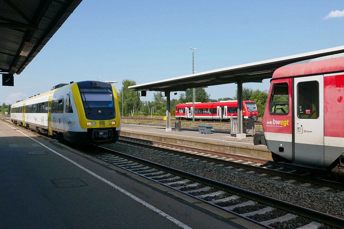 Blick zwischen einem schnell durchfahrenden und einem stehenden Zug auf den Mittelbahnsteig und einen abgestellten Triebwagen der Baureihe 650 im Bahnhof von Aulendorf. Ohne Halt durchfährt 612 515 als „Basel-Sprinter“ (IRE 3050, Ulm - Basel Bad Bf) am 28.08.2019 den Bahnhof Aulendorf.