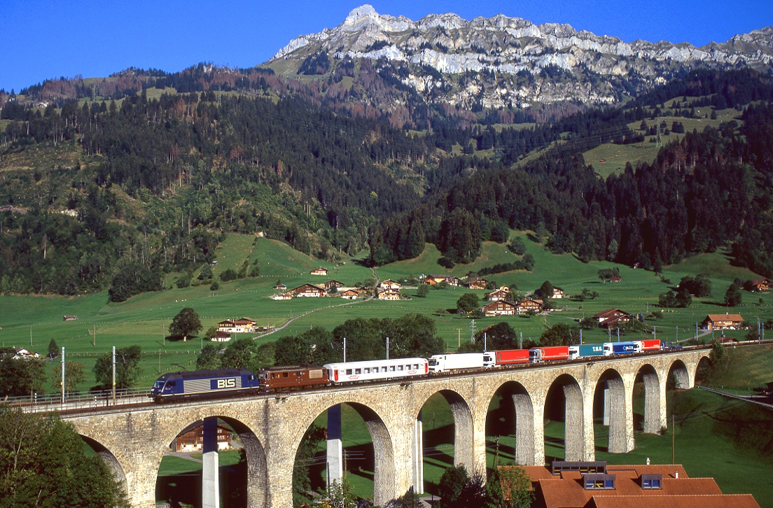 BLS 465 018 und 180 Rollen bei Frutigen mit einem mäßig beladenen Zug der Rollenden Landstraße die Lötschberg Nordrampe hinab, 15.09.2003.