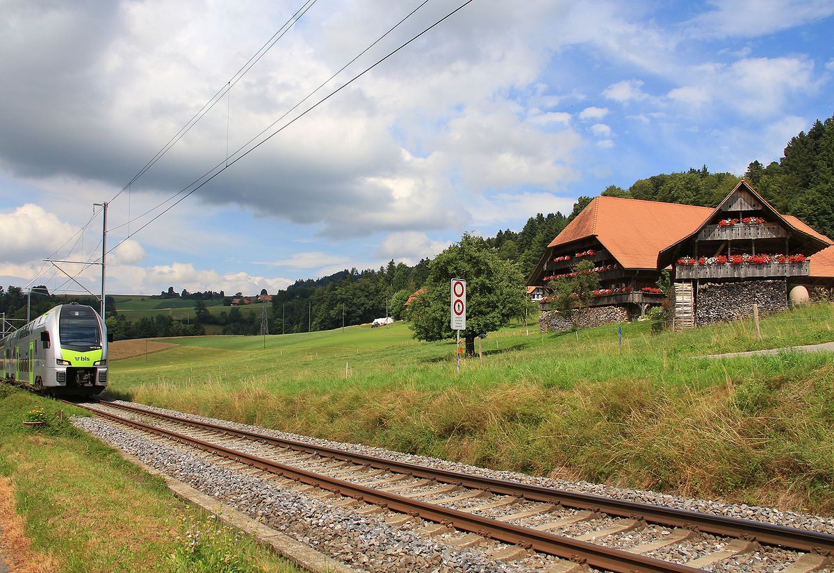 BLS  MUTZ (Serie 515) der S-Bahnlinie Bern - Schwarzenburg: Bauernhof mit Stöckli (Nebengebäude für die zurückgezogenen Aelteren) in Aeckenmatt. Zug 515 020 schleicht sich ins Bild. 10.Juli 2017 