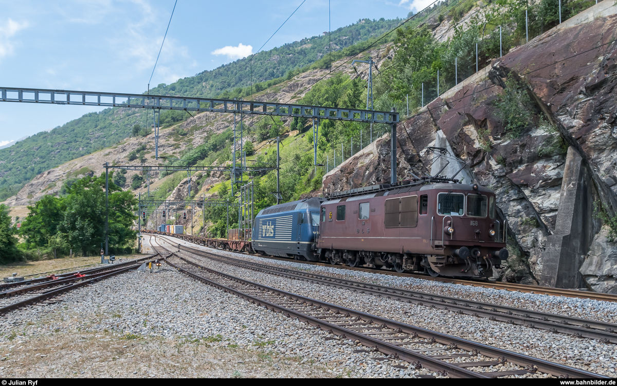 BLS Re 4/4 168  Baltschieder  (noch mit Chrombuchstaben) leistet einer unbekannten Re 465 am 24. Juni 2017 Vorspann über die Lötschberg-Bergstrecke. Bei dem fast leeren Zug ist fraglich, ob das nötig gewesen wäre, mich hat die Bespannung aber sehr gefreut. Aufgenommen bei der Durchfahrt in Lalden.