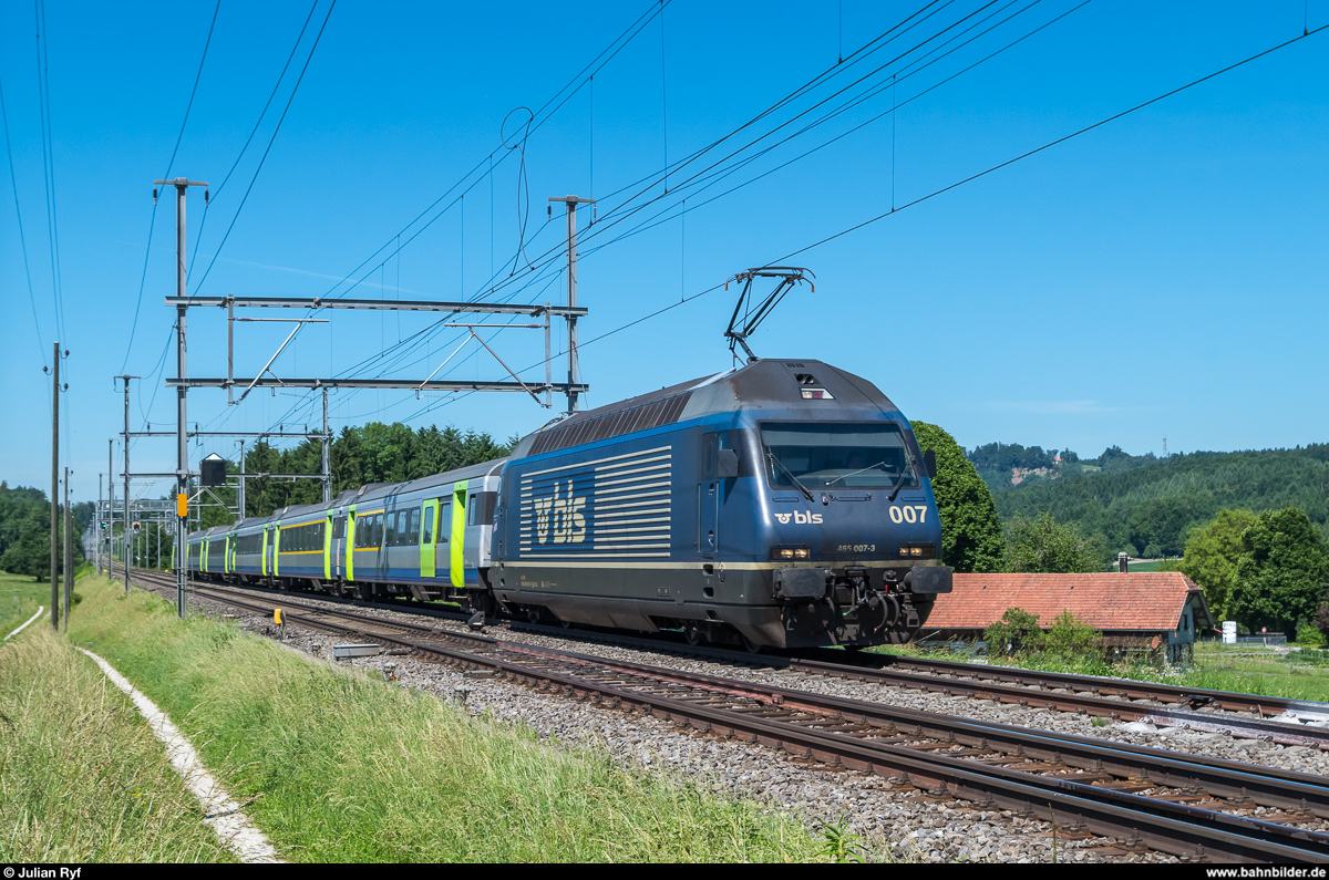 BLS Re 465 007 mit einem EW-III-Pendel als RE La Chaux-de-Fonds - Bern am 11. Juni 2017 bei Riedbach. Auf der anderen Seite der Gleise soll in wenigen Jahren eine neue Werkstätte der BLS entstehen. Das kleine Waldstück im Hintergrund und der Hof müssen weichen.