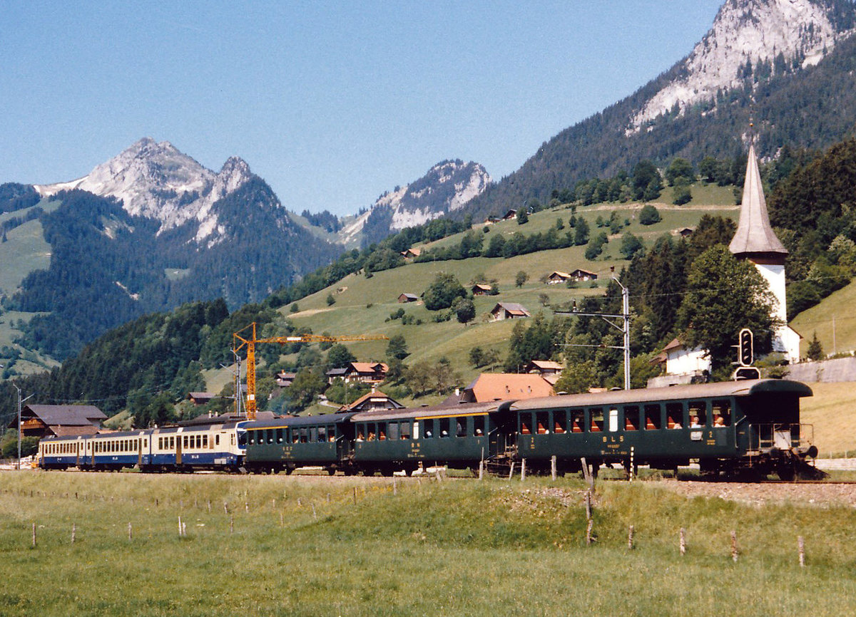 BLS/BN/SEZ: Auch nach der Inbetriebnahme der damals neuen RBDe 565 Pendelzügen im Jahre 1982 waren die alten Personenwagen mit den offenen Plattformen immer noch unentbehrlich. Der im April 1984 auf der Fahrt nach Zweisimmen bei Boltigen abgelichtete Zug war interessanterweise mit je einem Wagen von BLS, SEZ und BN verstärkt worden. 
Foto: Walter Ruetsch  