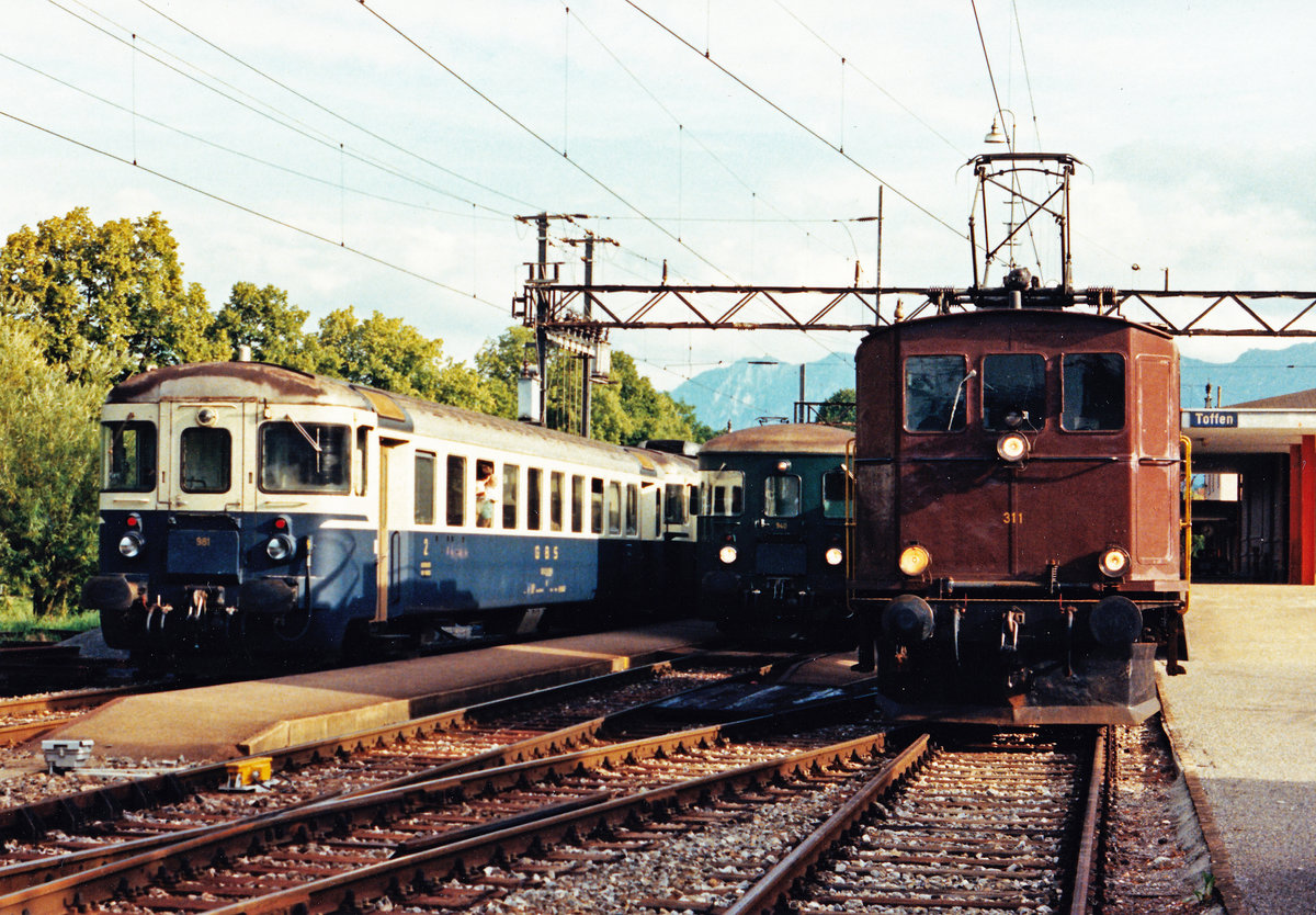 BLS/GBS:
Impressionen der Gürbetal-Bern-Schwarzenburg-Bahn (GBS).
Im August 1987 wurde die alltägliche Zugskreuzung von zwei Regionalzügen in unterschiedlichen Farben sowie dem Postzug Thun-Bern mit der Ce 4/4 311 in Toffen verewigt.
Foto: Walter Ruetsch 
