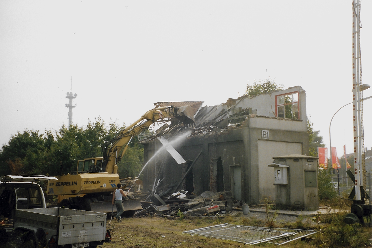 Borken (Westf.): Abriß des Stellwerks Bf (alt) nördlich des Bahnhofs am 15.09.1999, ca. 14 Uhr. Rechts im Bild sieht man noch Teile der alten Bahnschranken vom BÜ Ahauser Straße. Dahinter wehen schon die Fahnen des McDonalds.